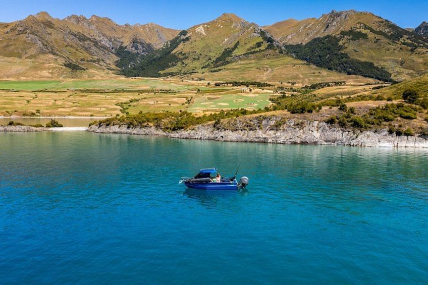 A boat on a clear blue lake surrounded by mountains. 5