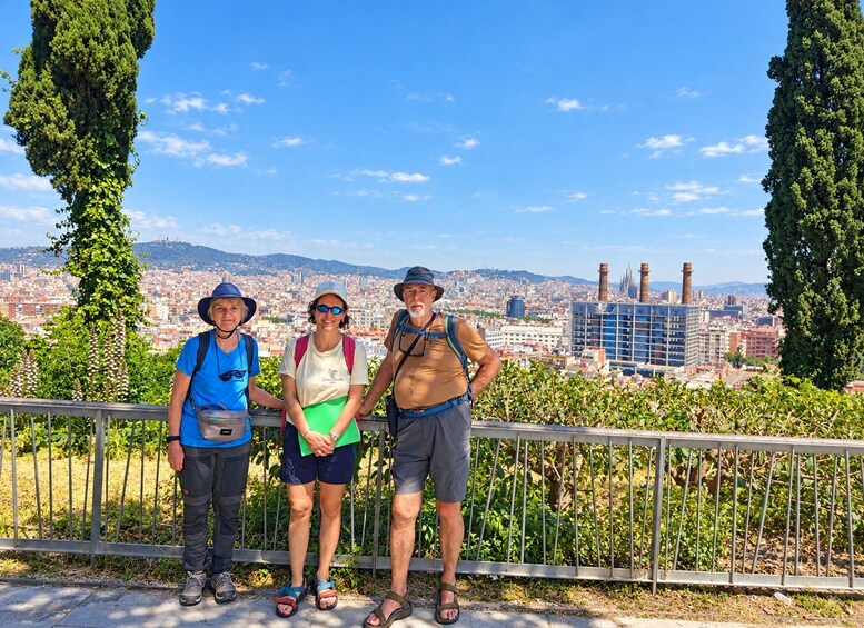 Three people standing on a viewing platform with a cityscape in the background. 2