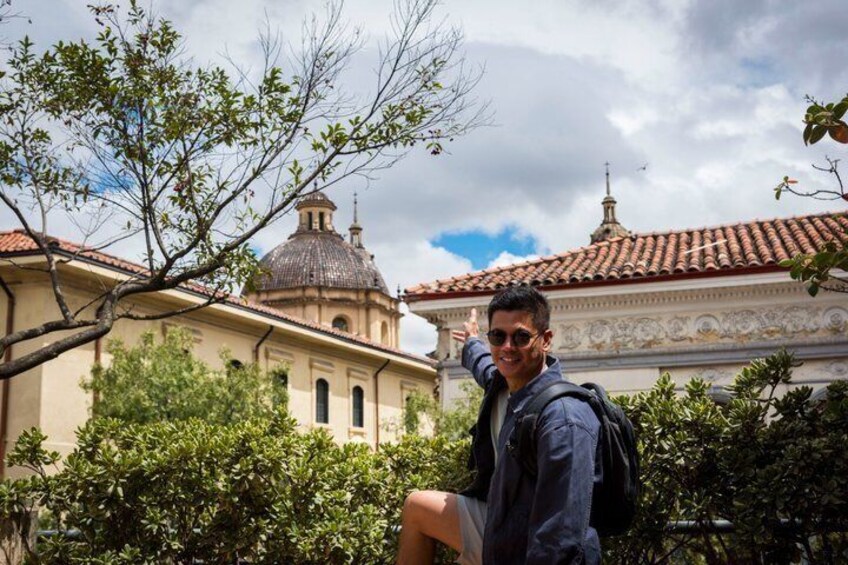 A person standing in front of a building with a dome and tiled roof. 5
