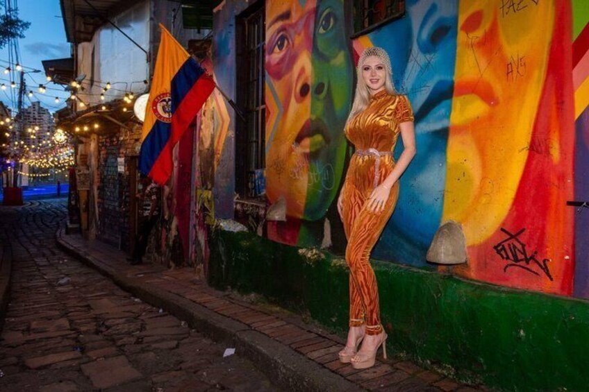 A street with colorful murals, a woman in a dress, and flags. 3
