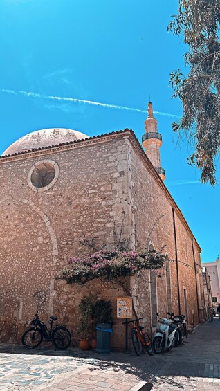 A historic building with a dome and minaret, surrounded by parked bicycles and scooters. 2