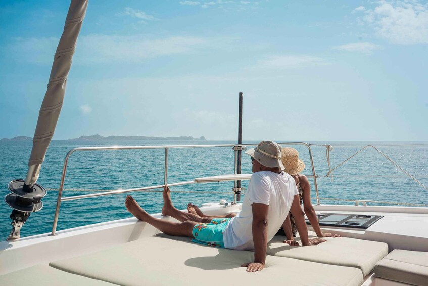 A man and a woman on a sailboat, with the sea and distant land visible. 3