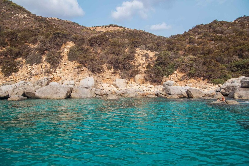 A turquoise sea with rocky shores and a mountainous backdrop. 4