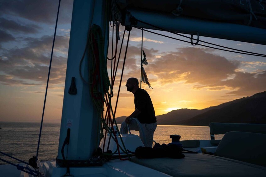 A person on a boat at sunset with mountains in the background. 5