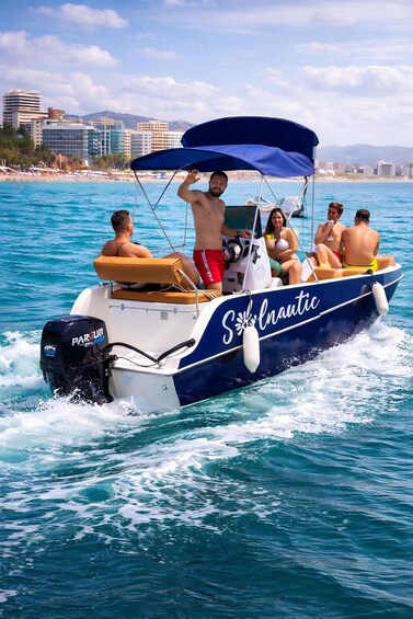 A boat with 'Sailnautic' branding on the side, people on board, and a cityscape in the background. 5