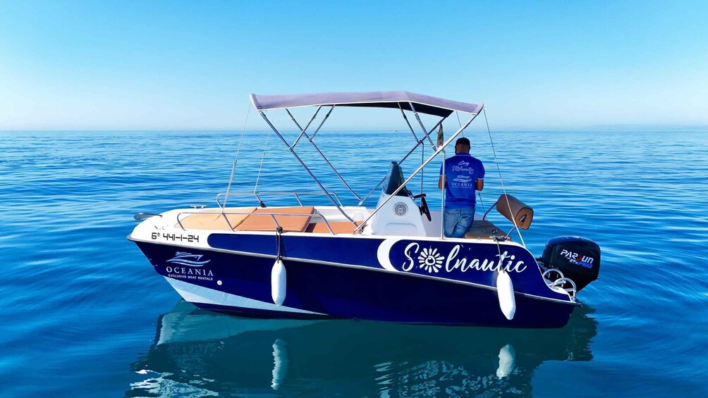 A blue and white boat named 'Oceania' on calm water. 2