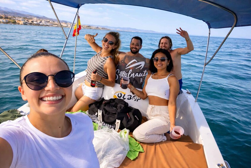 A group of people on a boat with a flag, a cityscape in the background, and calm waters. 1