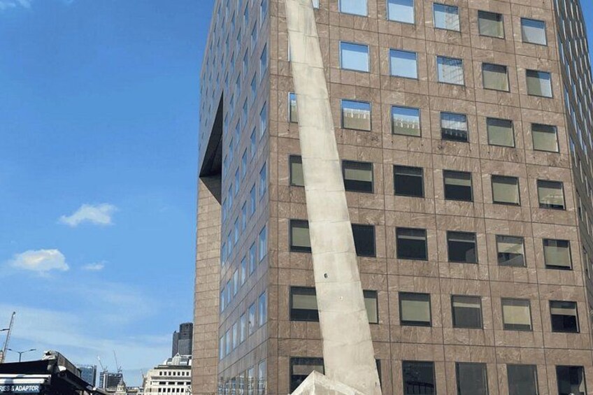A tall building with a unique architectural feature, a large concrete pillar, and a clear blue sky. 5