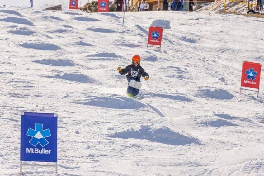 A skier on a snowy slope with flags and a blue sign with a star symbol. 2
