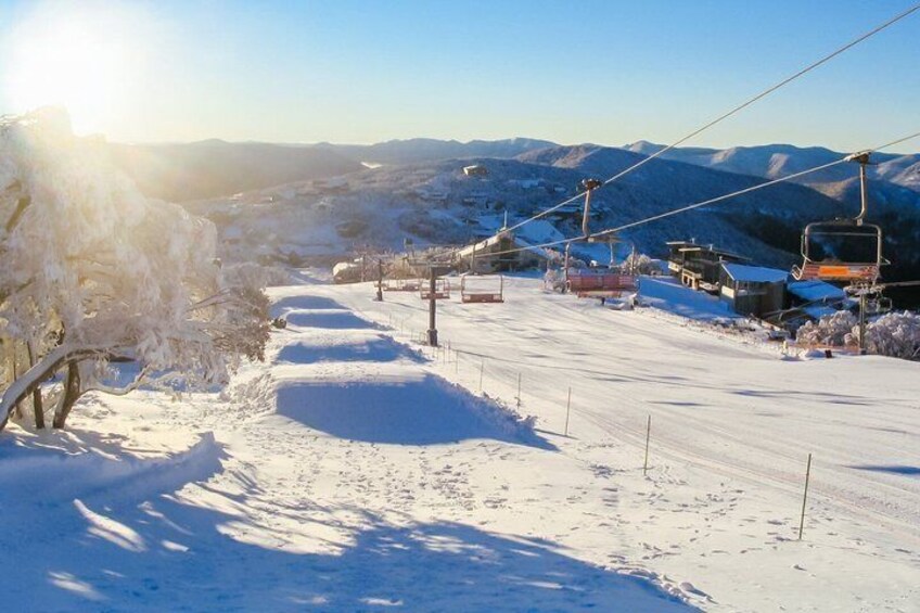 A snow-covered ski slope with ski lifts and a clear sky. 3