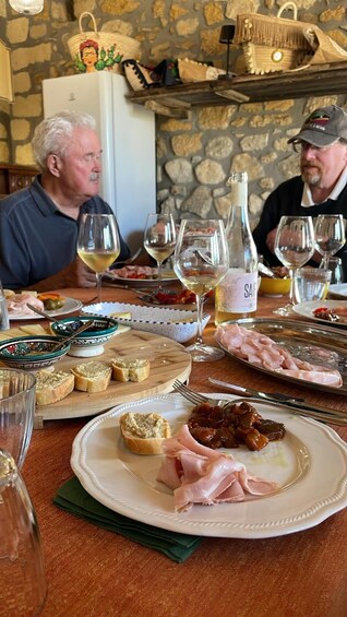A dining table with various dishes, glasses of wine, and a bottle labeled 'SAIF.' 2