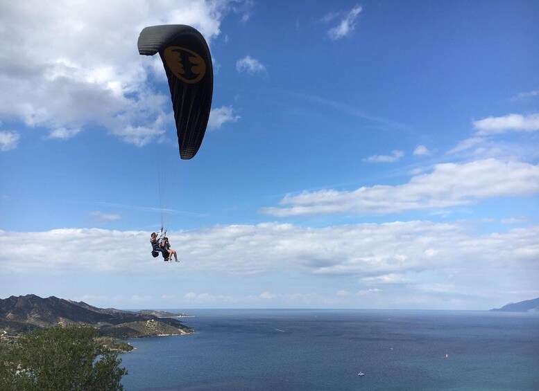 A paraglider over a coastal landscape with mountains and the sea. 4