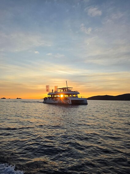 A boat with 'CATABEACH' written on its side sailing on the water during sunset. 5