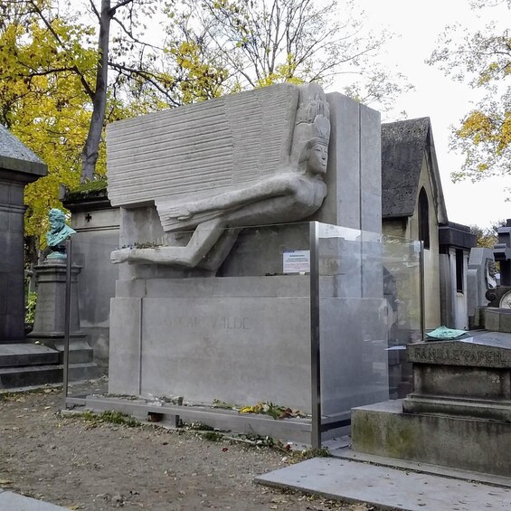 A large stone sculpture of a reclining figure with inscriptions, surrounded by cemetery headstones. 2