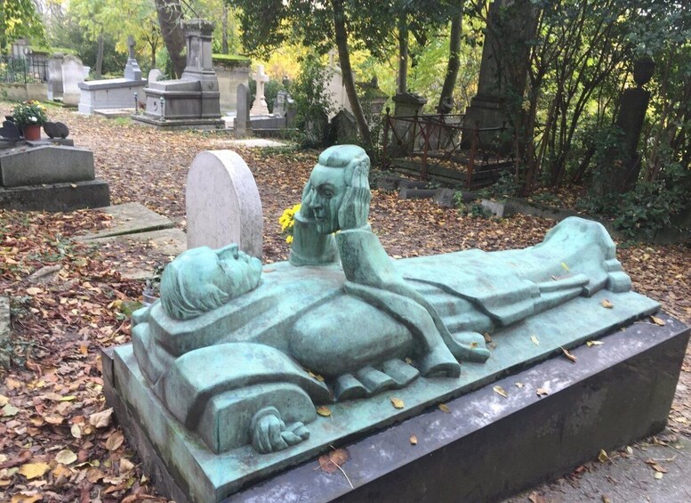 A cemetery with gravestones and a prominent statue of a reclining figure. 1