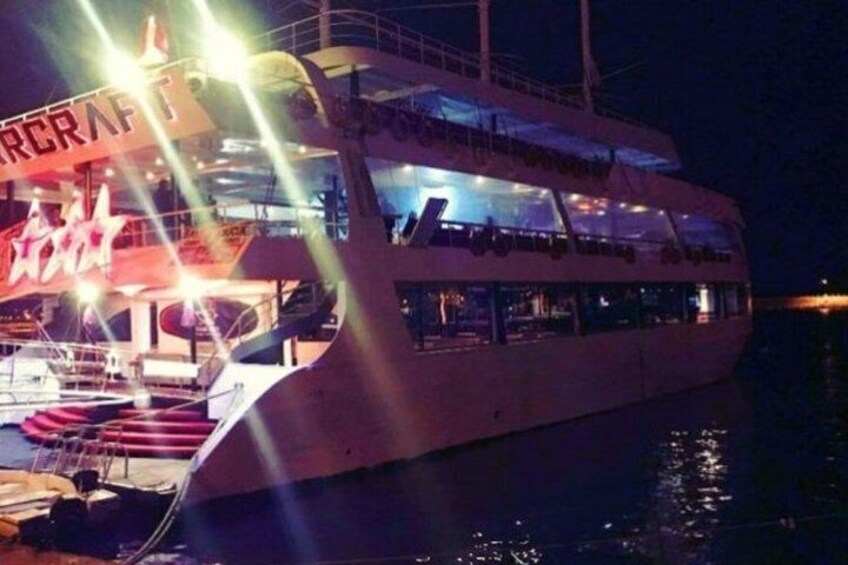 A large white boat with a sign reading 'AIRCRAFT' and a lit-up area on the deck. 3