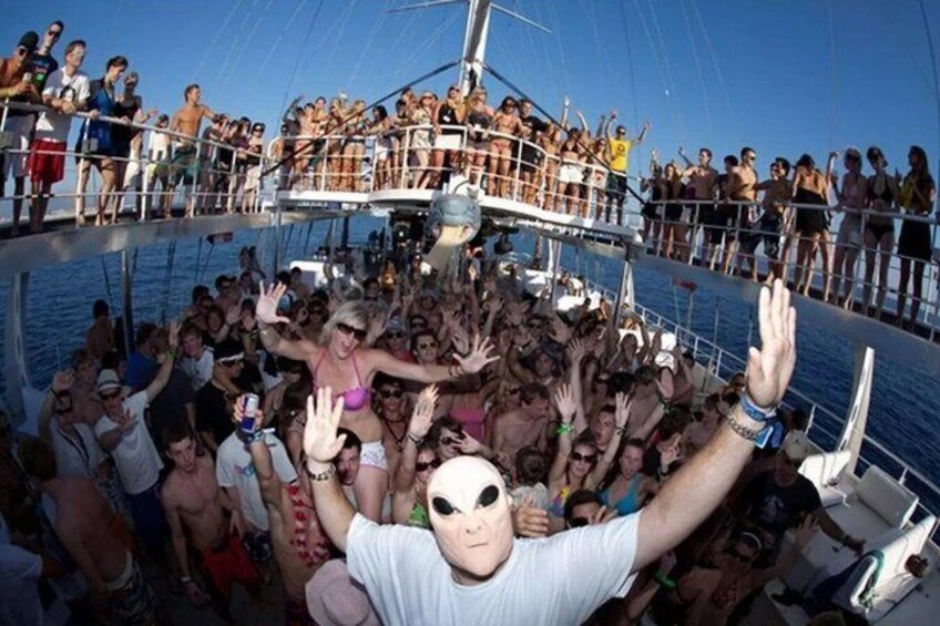 A crowded boat with people on deck and on the water. 2