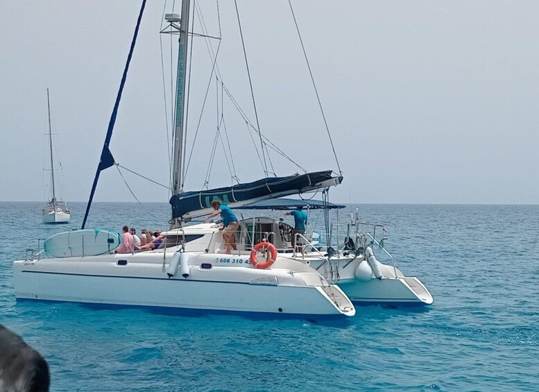 A sailboat with passengers, a lifebuoy, and another sailboat in the background. 4
