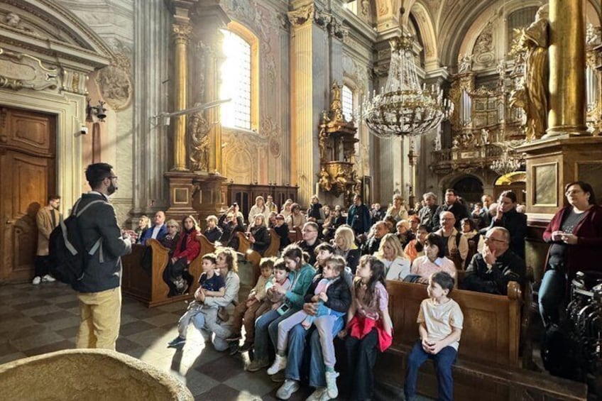 A crowded church interior with ornate architecture and a chandelier. 1