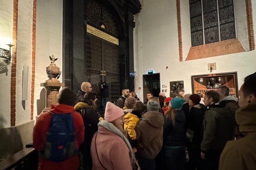 A group of people inside a building with a large arched doorway and a statue on a pedestal. 5