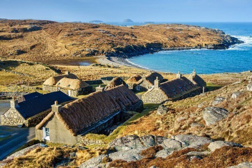 A coastal village with thatched-roof houses, rocky terrain, and the sea in the background. 2
