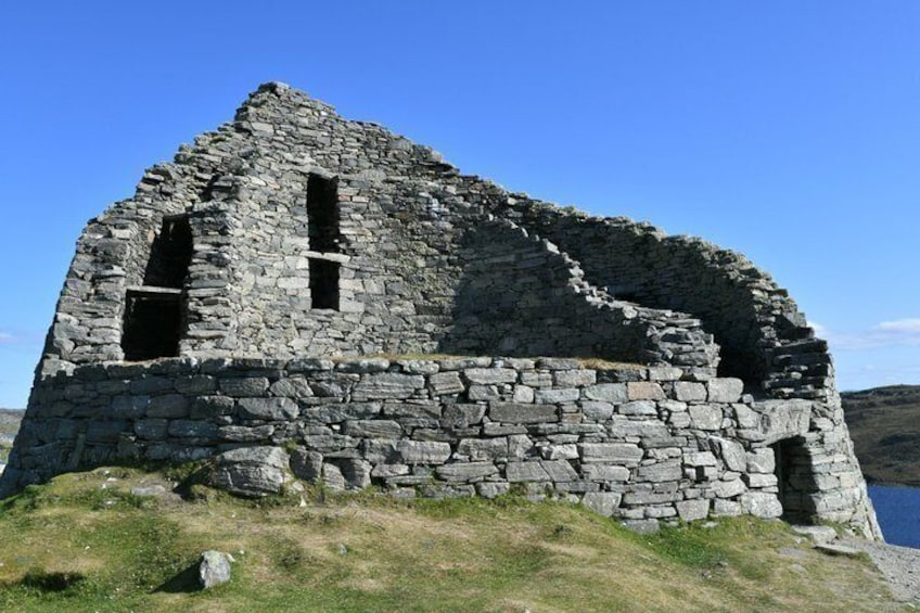 A stone ruin with two visible windows and a grassy foreground. 3