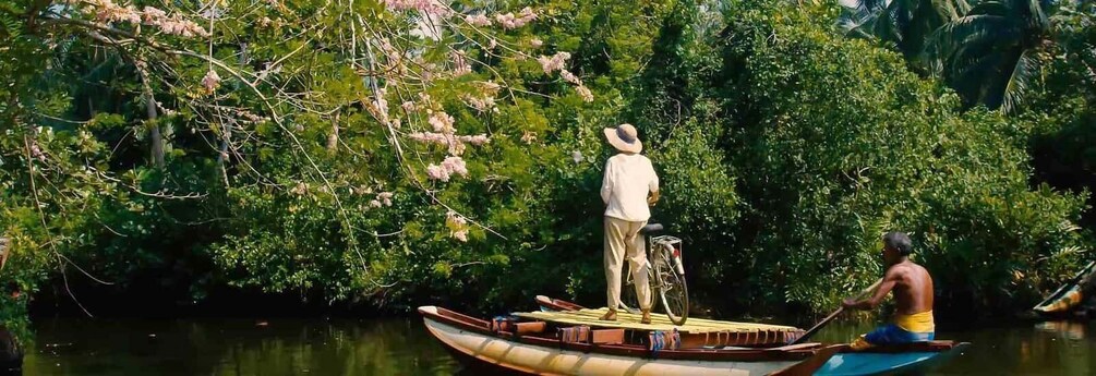 A man standing on a boat in a river surrounded by dense greenery. 2