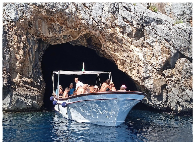A boat with passengers near a rocky cave entrance. 1