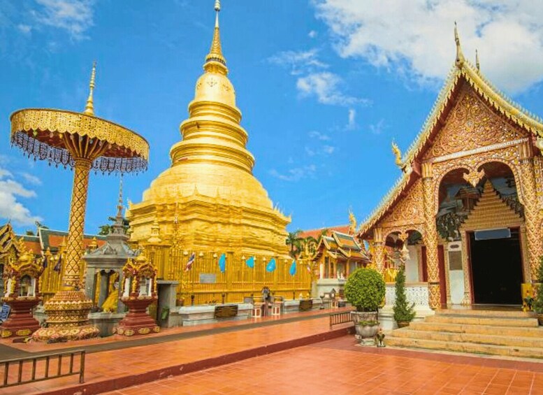 A golden stupa surrounded by ornate temple structures and a clear blue sky. 1