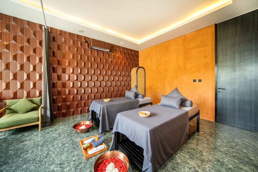A spa room with two massage beds, a green sofa, and a wooden wall with hexagonal patterns. 2