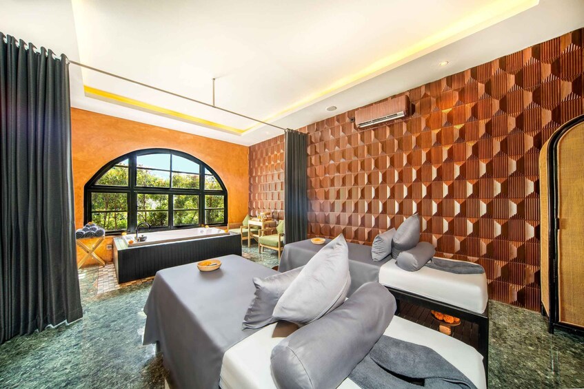 A modern spa room with a massage table, a sofa, and a large window. 4
