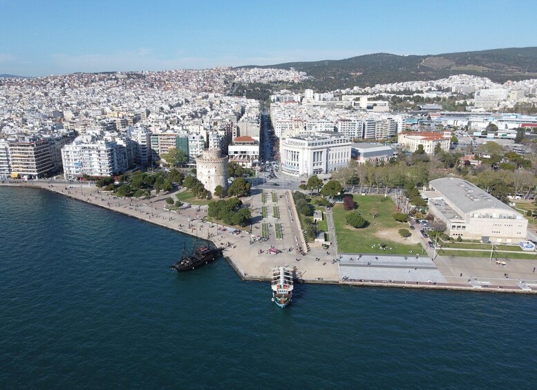 A coastal cityscape with a prominent tower, a large building with a curved roof, and a body of water with a boat. 4