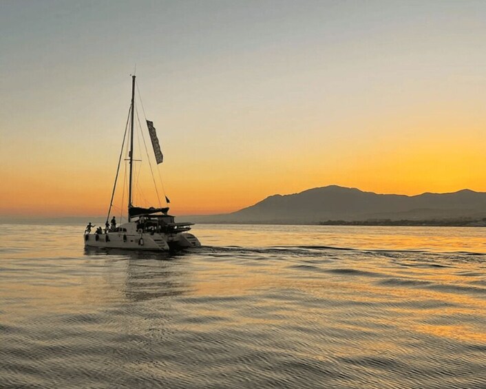 A sailboat on calm waters during sunset with mountains in the background. 1
