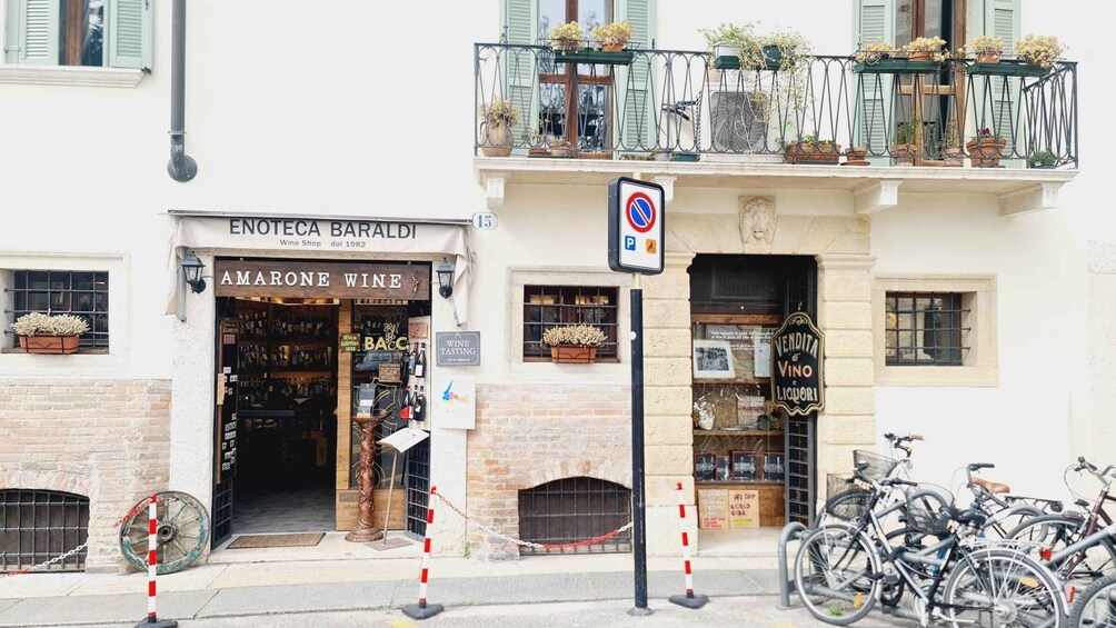 A wine shop named 'Enoteca Baraldi' with a 'No Parking' sign, a wine tasting sign, and bicycles parked outside. 1