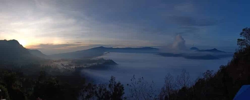 A mountainous landscape with a sunrise or sunset, mist over the valleys, and distant mountains. 4