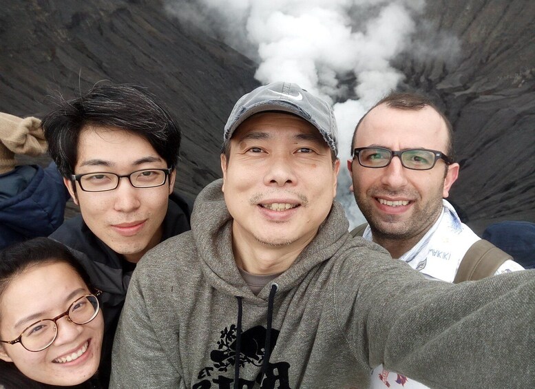 A group of people near a volcanic crater with smoke. 3
