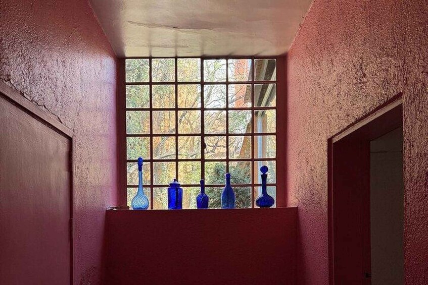 A window with a grid pattern, a red wall, and blue vases on a shelf. 2