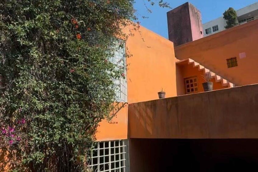 A building with orange walls, a staircase, and a tree with pink flowers. 3