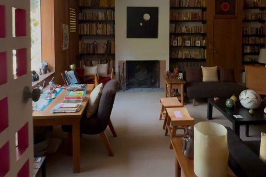 A cozy library with bookshelves, a fireplace, a sofa, and a dining table. 5