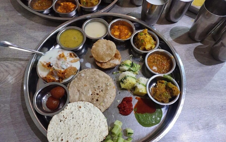 A traditional Indian meal with various dishes and accompaniments on a metal plate. 2