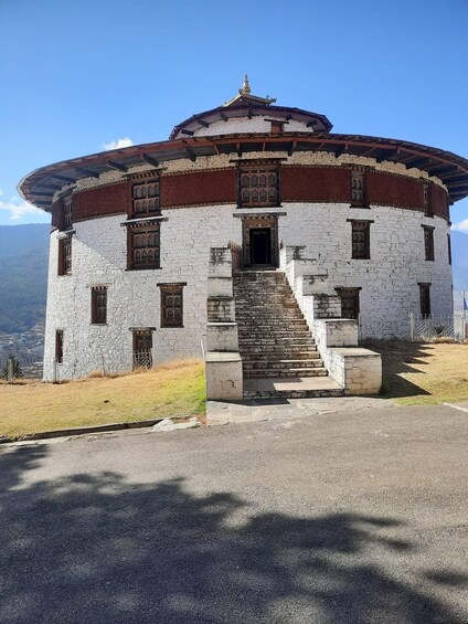 A traditional building with a circular structure, a staircase leading to the entrance, and a clear sky in the background. 3