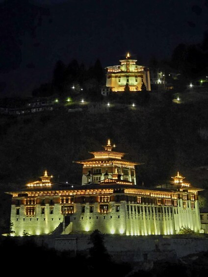 A brightly lit temple complex with multiple pagodas on a hill. 1