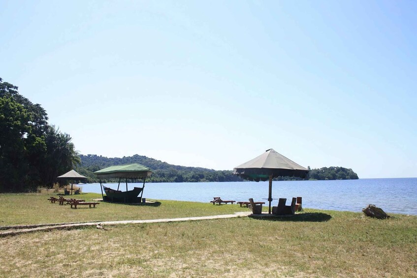 A lakeside picnic area with tables, umbrellas, and a boat. 2