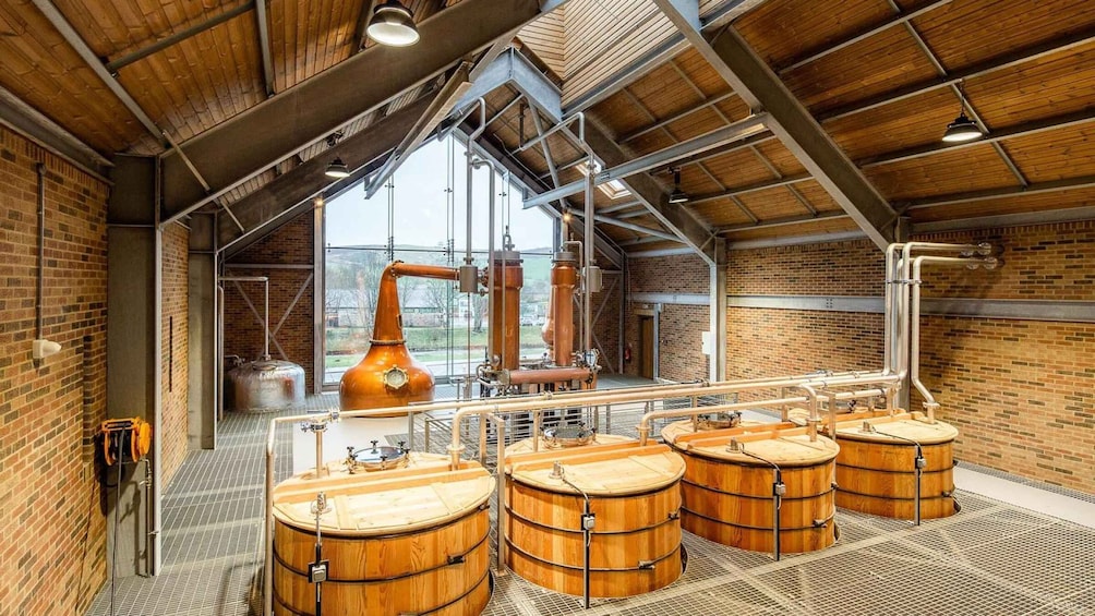 A distillery interior with wooden barrels, copper stills, and brick walls. 5