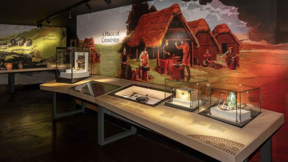 An exhibit with artifacts in glass cases, a mural depicting a traditional scene, and a sign reading 'A Place of Creativity.' 4