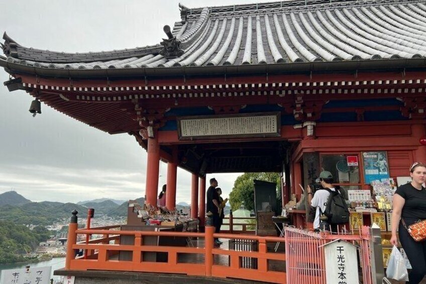 A traditional Japanese temple with a red roof and a signboard. 4
