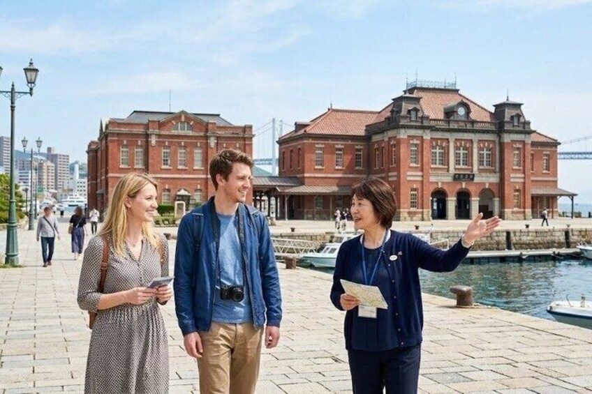 Three people standing on a waterfront promenade with historic buildings in the background. 1