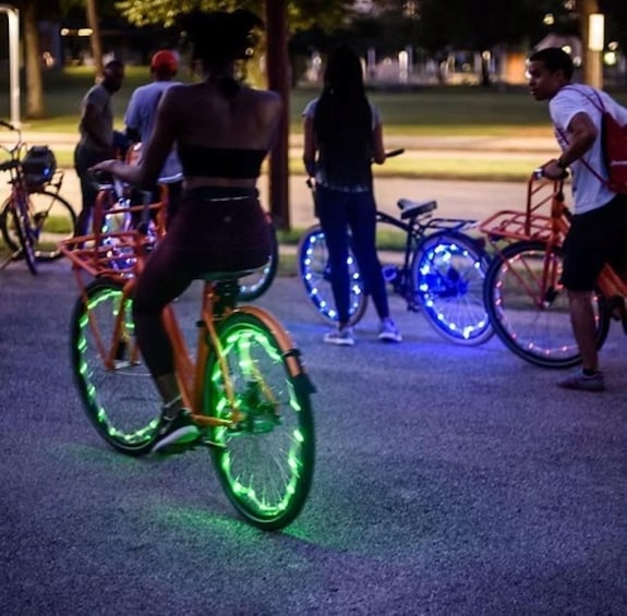 A person riding a bicycle with neon lights on the wheels. 1