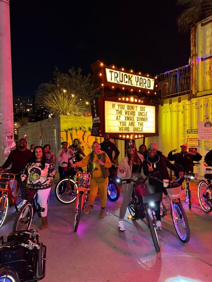 A group of people with bicycles in front of a neon-lit sign that reads 'TRUCK YARD.' 5