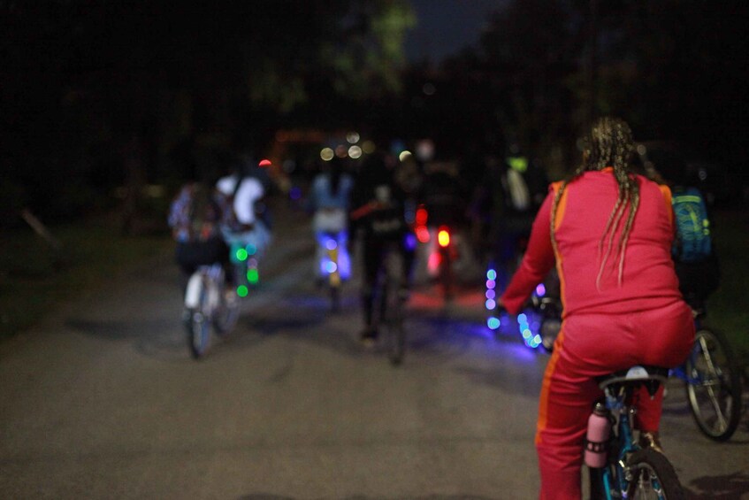 A nighttime scene with cyclists on a road, some with lights attached to their bikes. 4